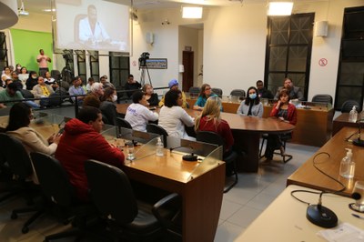 Plenário e Mesa Central, com participação de: Dévola Pilar de Gouveia Almeida, Gerente do Departamento de Redes de Atenção à Saúde, representando o Secretário Municipal de Saúde; Márcia Maria Ferreira de Oliveira, Presidente do Conselho Tutelar de Viçosa; Maria do Carmo Tito, Diretora da APAE de Viçosa; Lívia Ferreira Santana, coordenadora do Setor de Inclusão da Secretaria Municipal de Educação; Michelle Mello Gomes, coordenadora do Setor de Passe Livre da Secretaria Municipal de Assistência Social; Prof. Per Christian Braathen, Pró-Reitor Acadêmico da UNIVIÇOSA; Psicóloga Zélia Albernaz, que coordenou a primeira Farmácia Popular de Minas Gerais, em Viçosa; Psicóloga Marlene Moreira, idealizadora do grupo AlcaTEA (Grupo de Apoios às Famílias com TEA); Marina Adriana, mãe de autista e participante do grupo AlcaTEA; Prof.ª Michelle Nave Valadão, coordenadora da Unidade Interdisciplinar de Políticas Inclusivas (UPI) da UFV; e Advogado Rodrigo Giffoni Rodrigues, representando a OAB Viçosa, além dos vereadores Bartomélio da Silva Martins (Professor Bartô) (PT), Jamille Gomes (PT), Marco Cardoso (Marcão Paraíso) (PSDB), Marcos Fialho (sem partido) e Sérgio Marota (PL)